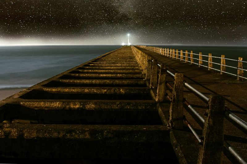 Staircase by sea against sky at night