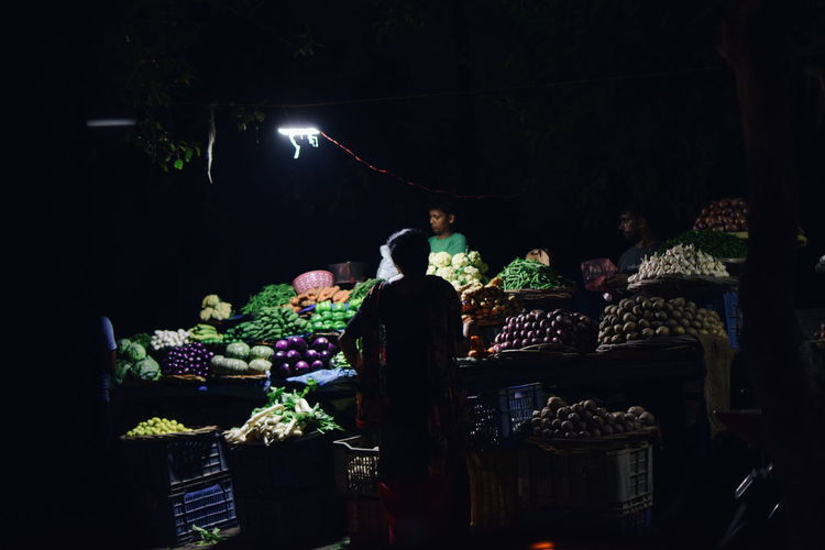 Man and vegetables in market at night