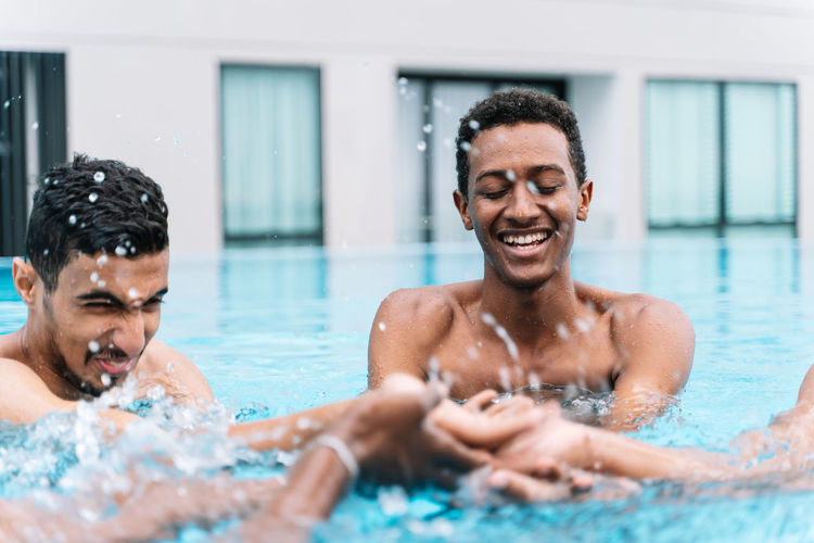 Young man smiling as he plays in a circle with a group of friends in a pool