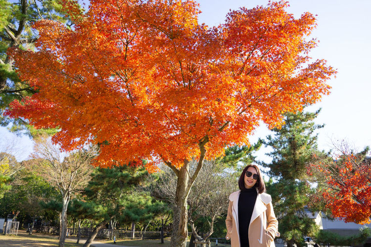 Portrait of woman standing by tree during autumn
