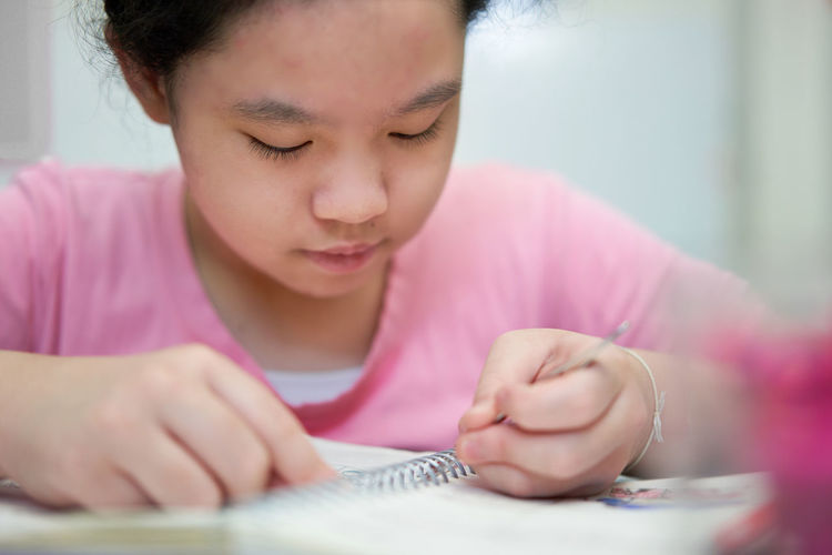 Close-up of girl drawing on book at home