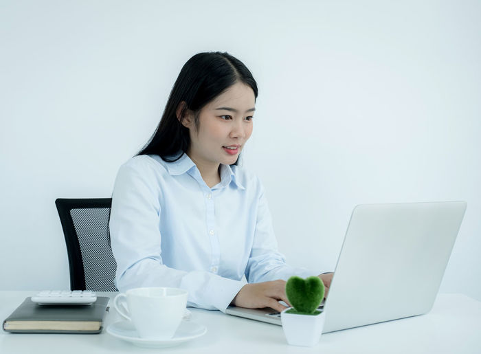 Young businesswoman using laptop while sitting at office