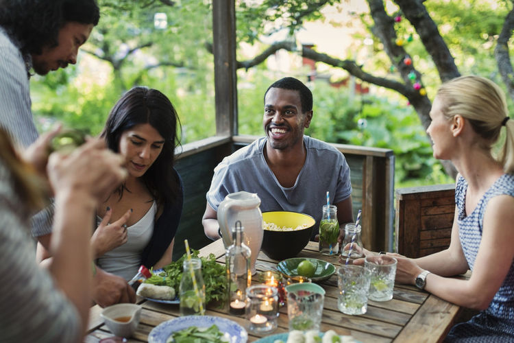 Multi-ethnic friends having food at porch in log cabin
