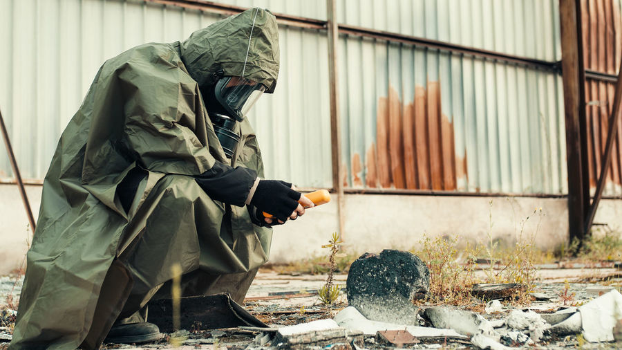 Man with geiger counter near radioactive barrels