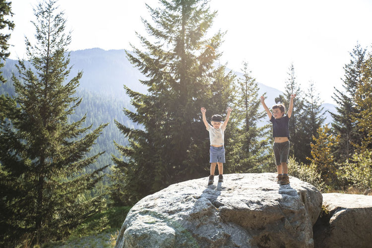 Two young hikers raise their hands in celebration, completing hike.