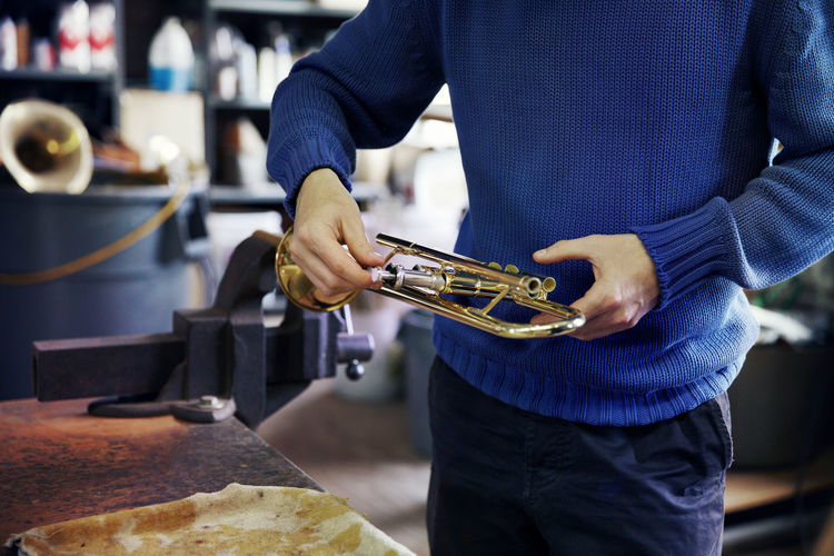 Midsection of man repairing trumpet