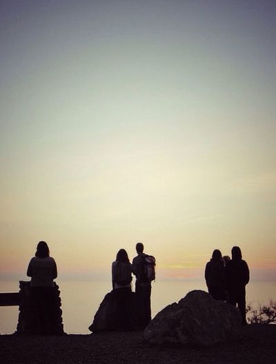 People sitting on rock at sunset