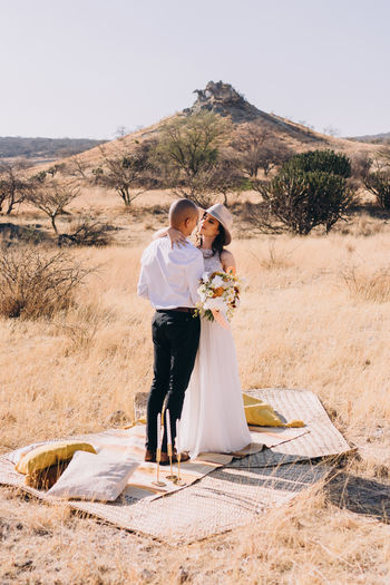 Full length of couple standing against sky