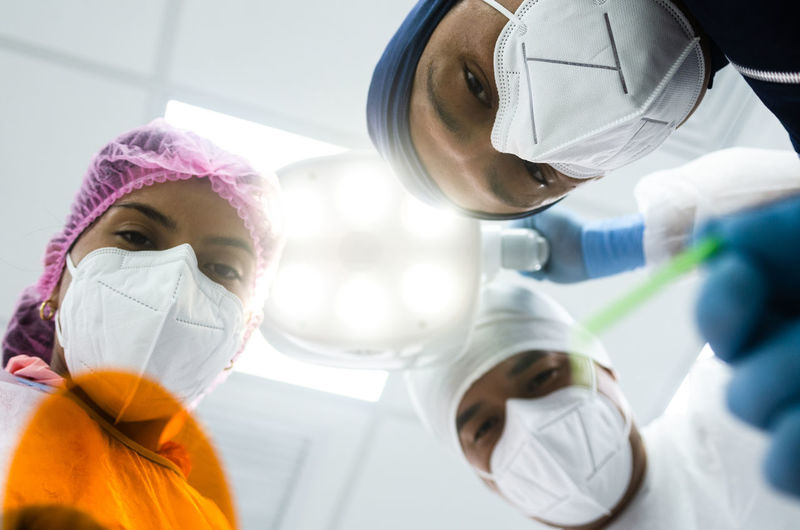 Low angle view of surgeons wearing mask in operating theater