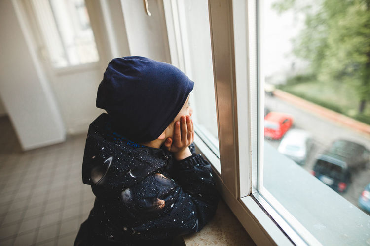Midsection of boy looking through window