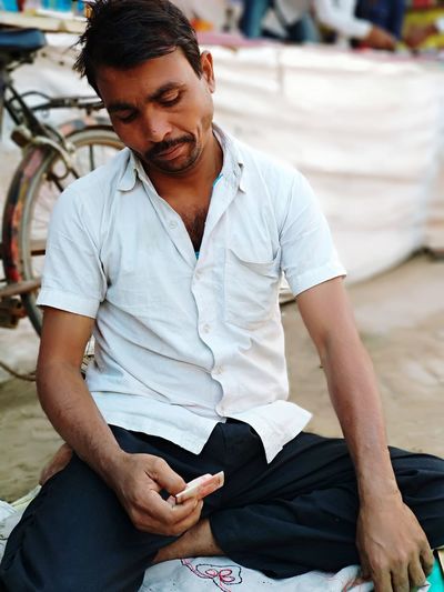 Close-up of man with paper currency sitting on road
