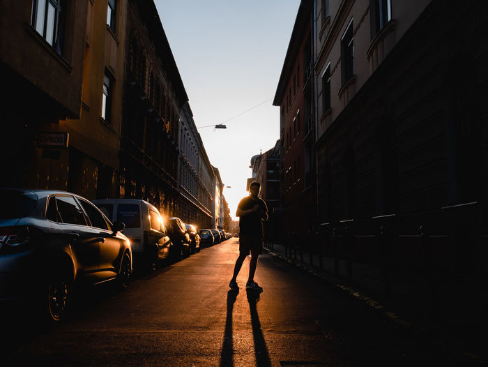 Rear view of woman walking on street amidst buildings in city