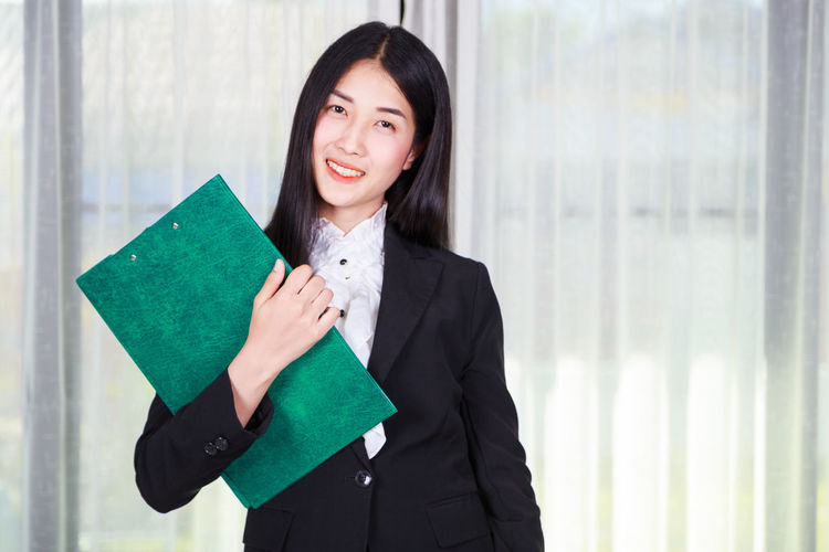 Portrait of smiling young woman holding file in office