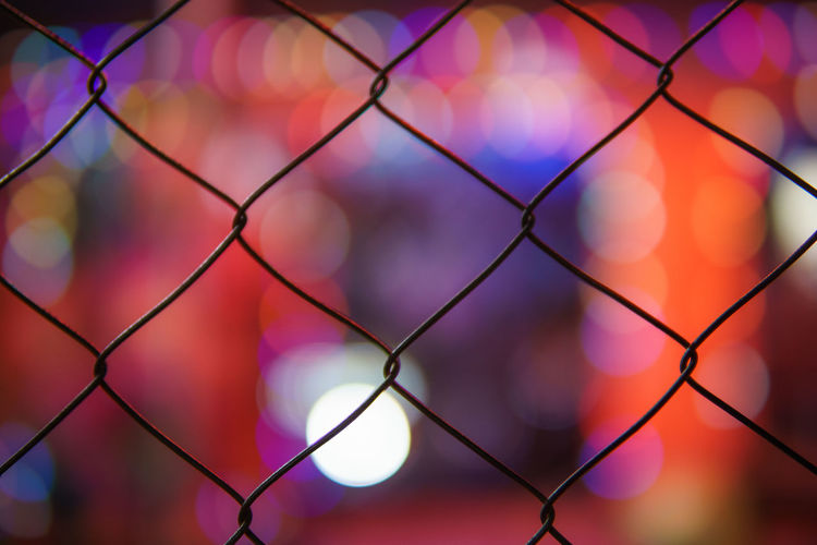 Full frame shot of chainlink fence against illuminated lights