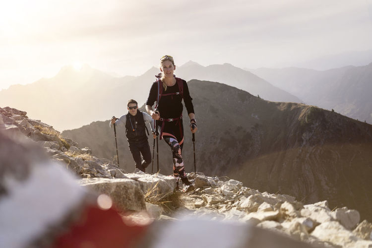 Sportsman and woman with hiking pole and backpack walking on mountain path of bschiesser at tyrol, austria
