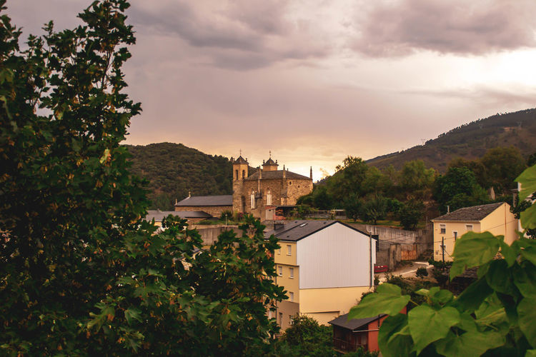 Castle in the middle of village with mountains in cloudy sunset