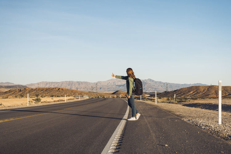 Woman hitchhiking on desert road, nevada, usa