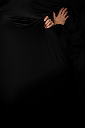 Midsection of woman standing against black background