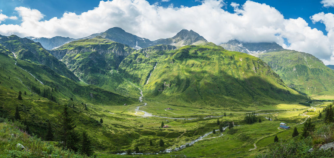 Green meadows and pastures surrounding alpine huts with mountains in the background, austria.
