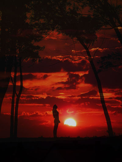 Silhouette person standing on field against orange sky