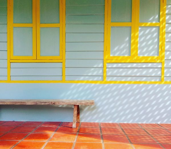 Empty wooden bench against closed windows