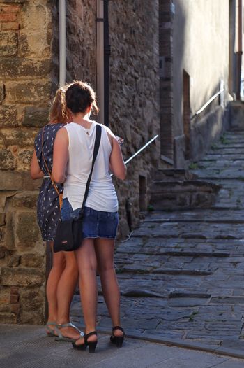 Rear view of two women looking at guidebook