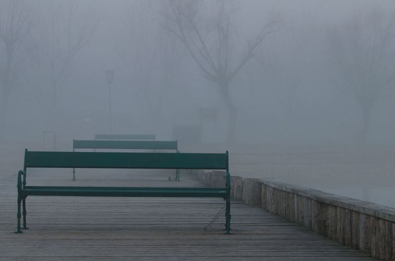 Empty bench in park during winter