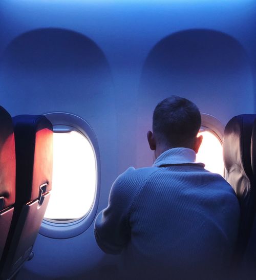 Rear view of man sitting in airplane