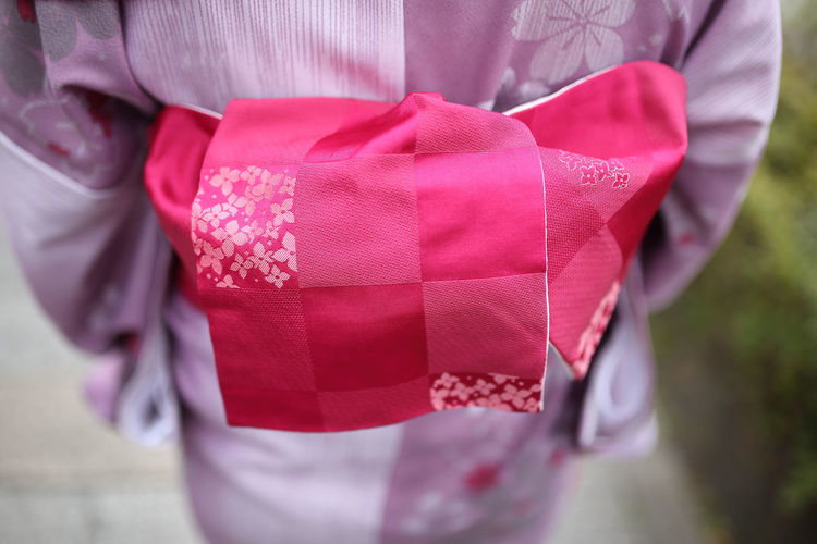 Close-up of woman holding pink umbrella standing in box