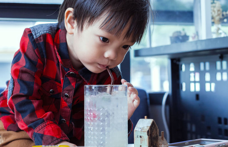 Cute boy drinking juice on table in restaurant