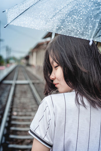 Portrait of woman on wet railroad track during rainy season