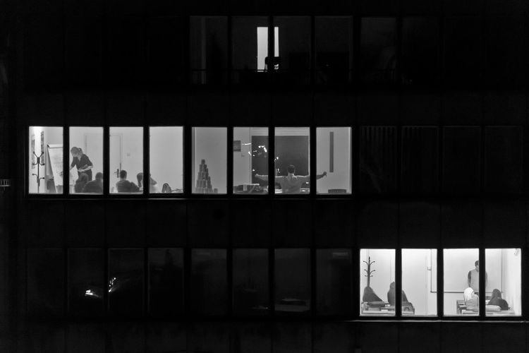 People in building seen through windows at night