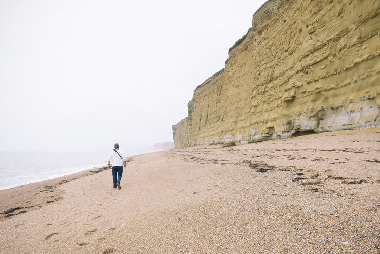 Rear view of man walking on beach 