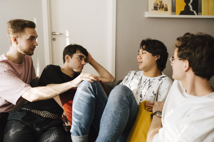 Multi-ethnic male friends comforting young man while sitting in living room