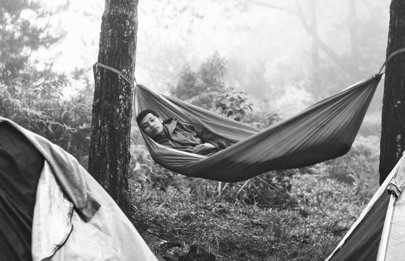Hiker resting on hammock in foggy forest