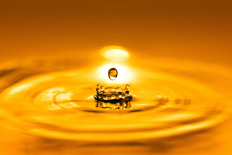 Closeup on drop of cosmetic golden oil liquid.