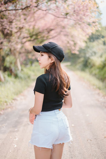 Young woman looking away while standing on road