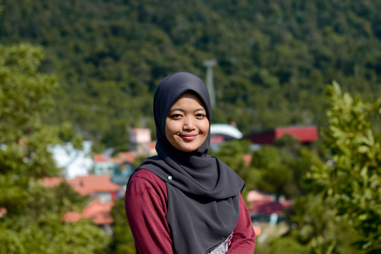 Portrait of smiling young woman standing against plants