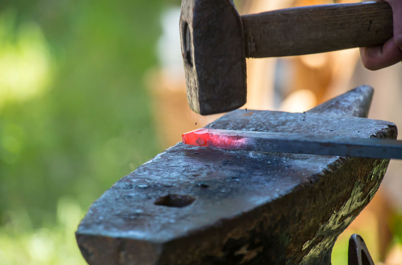 Close-up of metal and hammer on anvil at workshop