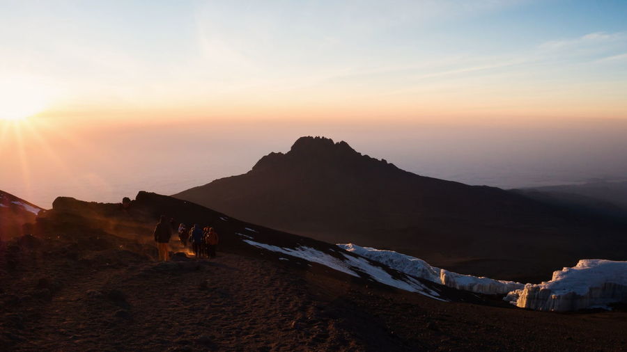 Hikers at mt kilimanjaro against sky during sunset