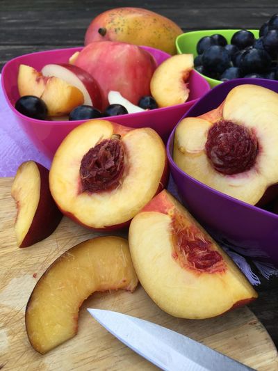 Close up of cut nectarines and bowls of fruit