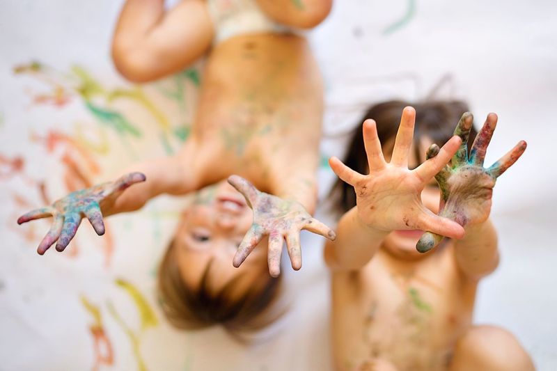 High angle view of shirtless siblings playing with paints