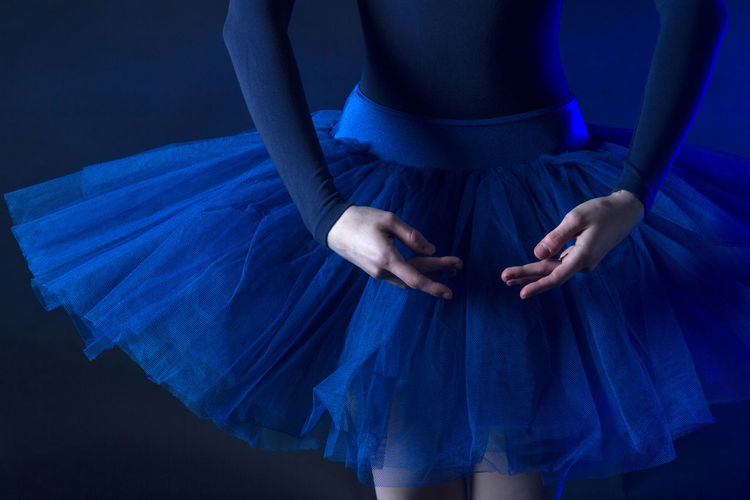 Midsection of dancer standing against blue background