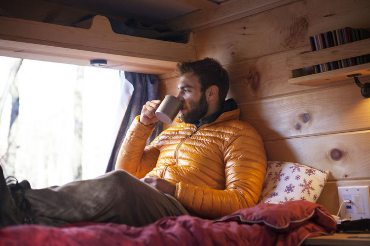 Man having drink while sitting in camper van