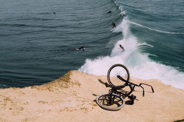 High angle view of bicycle with people surfing in sea