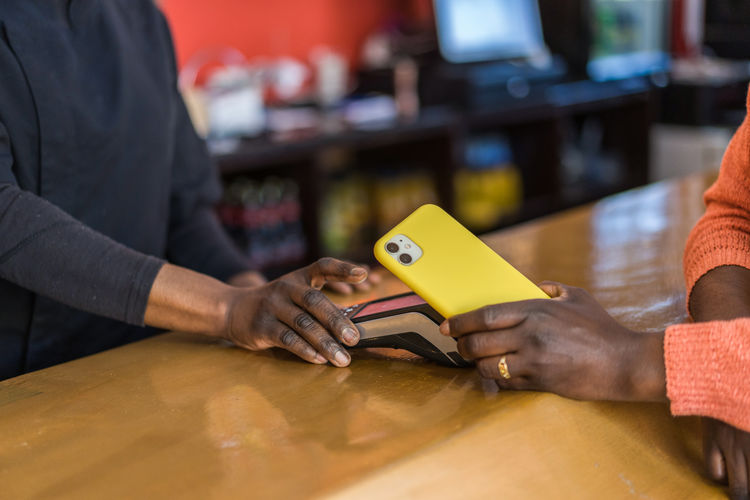 Crop unrecognizable customer making payment with plastic card on pos terminal at counter in bar person