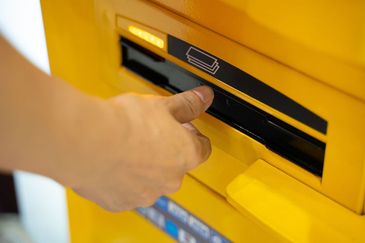 Close-up of hand holding yellow mailbox