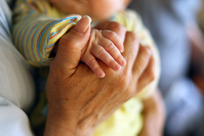 Close-up of grandma holding hands of baby