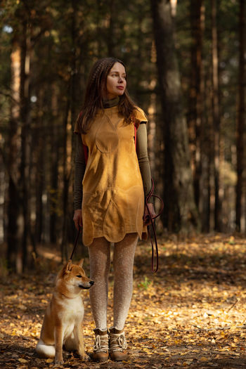 Beautiful woman walking shiba inu dog in fall forest. autumn mood