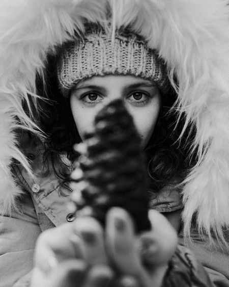 Close-up portrait of woman in fur coat holding pine cone